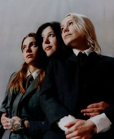 three women in suits and ties hugging each other