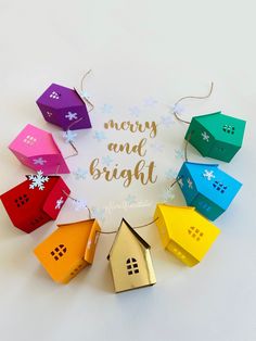 colorful origami house ornaments with merry and bright written on the front in gold