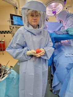 a woman in scrubs and protective gear standing next to an operating room