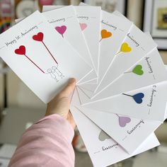 a person holding six cards with hearts on them