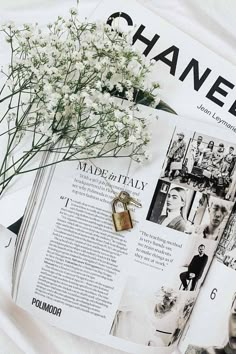 a bunch of white flowers sitting on top of a magazine next to a bottle of perfume