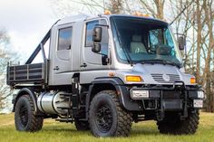 a large gray truck parked on top of a lush green field