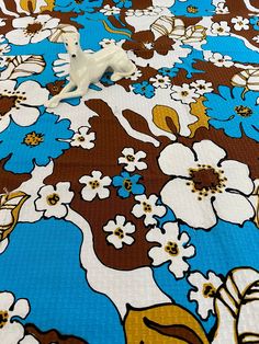 an animal figurine sitting on top of a blue and brown flowered bedspread