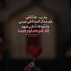 a person holding a heart shaped lollipop in front of a building with arabic writing on it