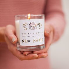 a woman holding a candle in her hands with the words new home printed on it