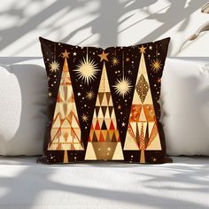 a decorative pillow with christmas trees on it sitting on a couch in front of a white wall