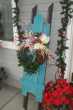 a blue chair with christmas wreaths and poinsettis on the front porch