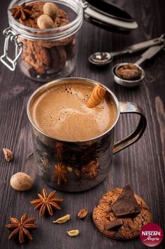 a cup of hot chocolate with cinnamon and star anise on the table next to it