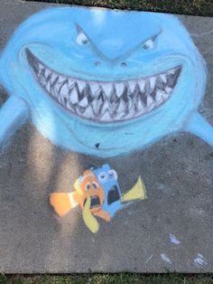 a chalk drawing of a shark and a fish on the ground next to each other