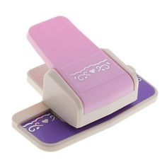 a pink and white plastic stapler with hearts on the side, sitting on top of a purple pad