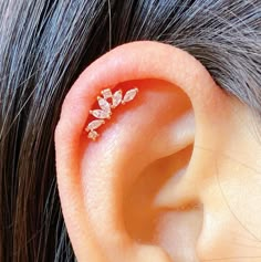 a woman's ear is adorned with three small white diamond leaf shaped studs