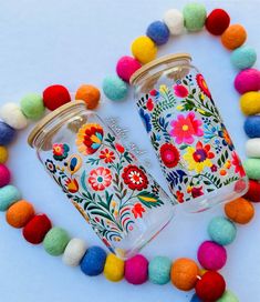 two mason jars decorated with colorful flowers and pom - poms