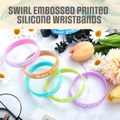 Our Embossed Printed Wristbands are similar to our Embossed Wristbands which are produced with raised text style but the difference is that they are additionally silk screen printed with ink. They exhibit an elevated graphical effect on the bands where the artworks or printed messages protrude out of the surface. The raised texts are printed with single or multiple colors through precise silk screen printing technology which vibrantly displays your customized message. To create a noticeable and attractive appearance, we recommend selecting contrasting colors for the bands and the ink. This is what makes these wristbands exceptional and out of the box promotional items for giveaways, advertising, and branding purposes. These 1/2 inch decorative wristbands are great promotional products for Silicone Bracelets, Promotional Items, Text Logo, Text Style, Promotional Item, Silk Screen Printing, Promotional Products, Wristbands, Silk Screen