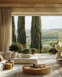 a living room filled with lots of furniture next to tall trees in front of a large window