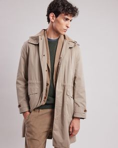 Men's long trench coat with a collar and drawstring waist. Removable hood and corduroy collar detail. Invisible button placket and front patch pockets. Adjustable buttons at the cuffs. Flannel-lined interior. Beige Chinos, Long Trench, Long Trench Coat, Cotton Coat, Style Chic, Button Placket, Mens Coats, Kids Accessories, Summer Collection