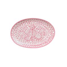 a pink and white plate with an ornate design on the rim, sitting against a white background