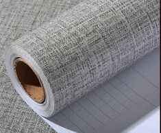 a roll of gray fabric sitting on top of a white sheet of paper next to a ruler