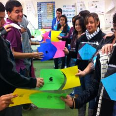 a group of people standing around each other holding up colorful pieces of paper in front of them