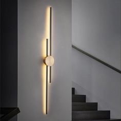 a modern light fixture on the wall next to stairs