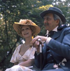 a man and woman sitting next to each other on a bench in the park wearing hats