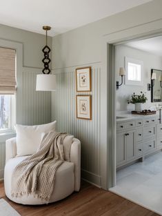 a living room filled with furniture and a white chair next to a window on top of a hard wood floor