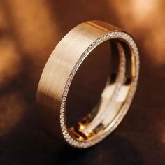 a gold ring with diamonds on it sitting on a brown surface in front of a blurry background