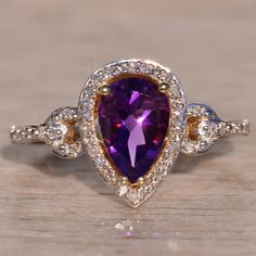 The 14th Avenue: Amethyst Halo Ring With Natural Diamonds In Yellow Gold. The Ring Centers On A 1.50 Carat Pear Brilliant Cut Natural Amethyst With Charming Purple Color. Surrounding The Center Is A Halo Of Round Cut Natural Diamonds. Diamonds Continue Into The Anchor Topped Shank. A Scrolled Filigree Finishes The Look Below The Center. The Ring Is Crafted In 14 Karat Yellow Gold And Is Currently A Finger Size 7 Yet Can Be Adjusted To Any Finger Size For An Additional Charge On Request. Amethyst And Diamond Ring, The Anchor, Halo Ring, Halo Rings, Womens Jewelry Rings, Purple Color, Wedding Rings Engagement, Round Cut, Natural Diamonds