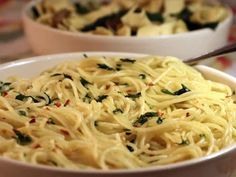 two bowls filled with pasta and spinach on top of a tablecloth covered table