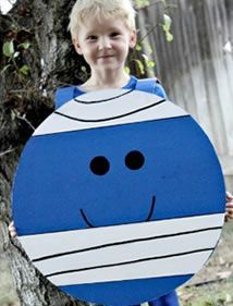 a young boy holding up a cardboard cut out of a cartoon character