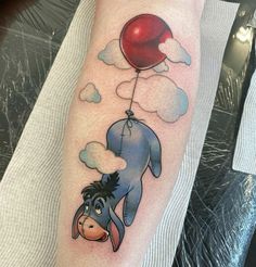 a person with a tattoo on their leg holding a balloon in the shape of a dog