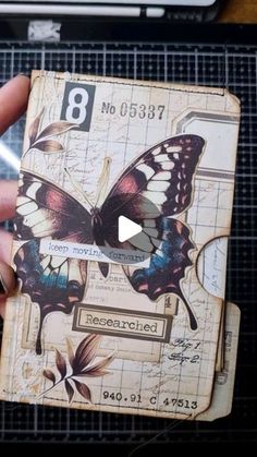 a hand holding an old book with butterflies on it and the number 8 in front