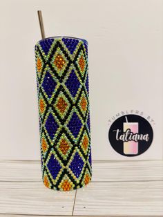 a blue, yellow and orange beaded tumbler with a straw sticking out of it