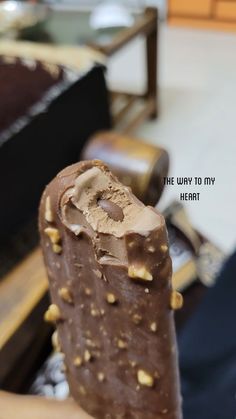 a person holding an ice cream bar with chocolate and nuts on it in their hand