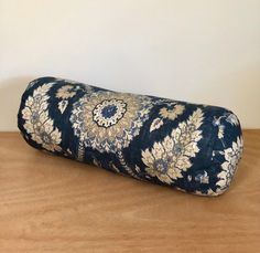 a blue and white pillow sitting on top of a wooden table next to a wall