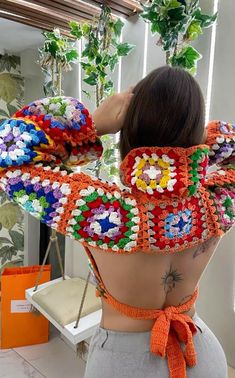 the back of a woman's top with colorful crocheted designs on it