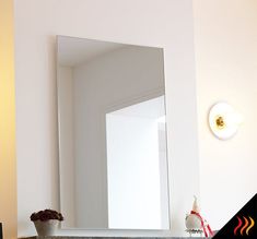 a mirror sitting on top of a counter next to a vase with flowers in it