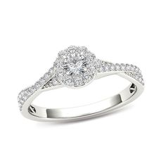 a white gold ring with diamonds on the band and a round center stone in the middle