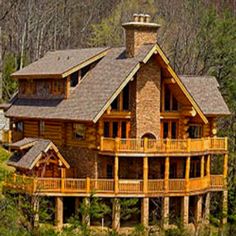 a large wooden house surrounded by trees in the woods with lots of windows and balconies