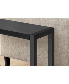 a black table sitting on top of a wooden floor next to a beige wallpaper