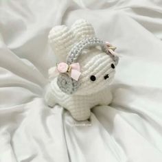 a crocheted white teddy bear with a pink bow on it's head