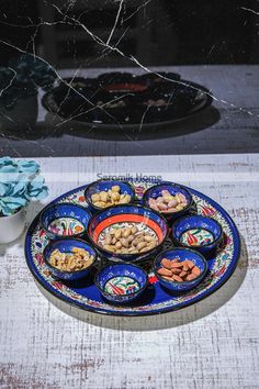 an assortment of nuts on a plate next to a vase with blue flowers in it