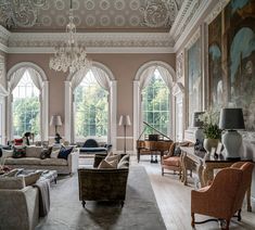 a living room filled with lots of furniture next to large paintings on the walls and windows