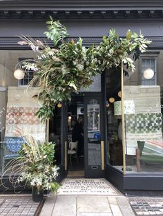 an entrance to a restaurant with plants growing out of it