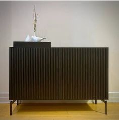 a black cabinet with two white birds on top and a plant in the corner next to it