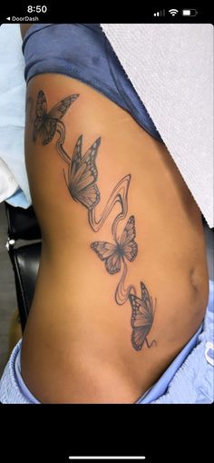 a woman's stomach with butterfly tattoos on her side and the bottom part of her belly