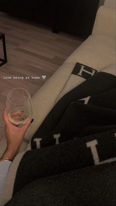 a woman holding a glass of wine on top of a couch in a living room