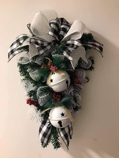 a christmas wreath hanging on the wall with ornaments attached to it and ribbons around it