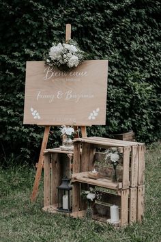 a wooden sign sitting on top of a grass covered field next to a bunch of flowers