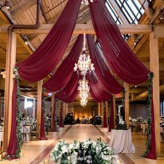 an indoor wedding venue with red drapes and chandelier hanging from the ceiling