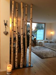 a living room filled with lots of furniture and tall wooden trees in front of a window